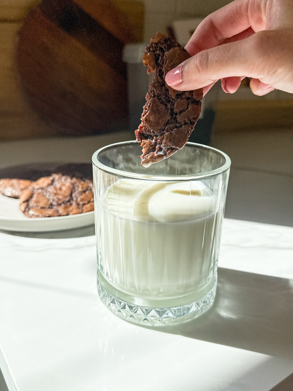 A cookie gets dipped into a glass of milk