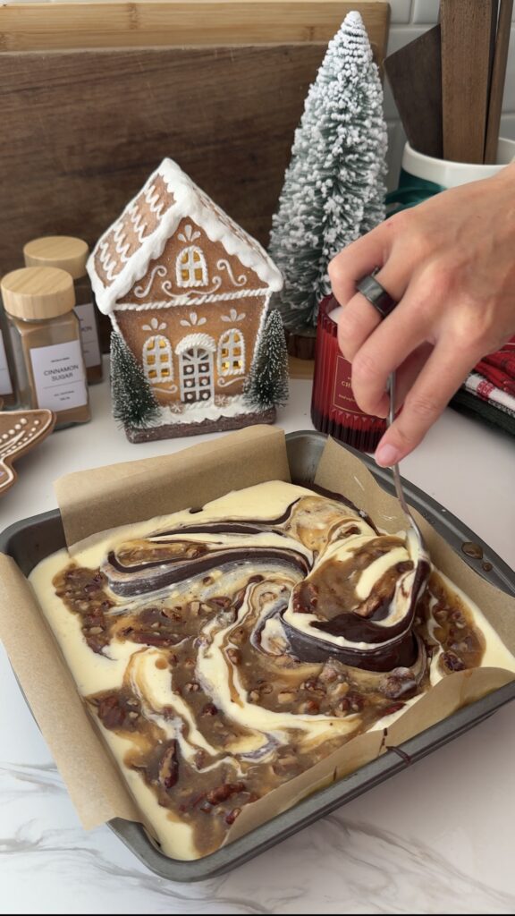 Swirling pecan mixture with cheesecake mixture in the baking pan before baking (image 3/3)