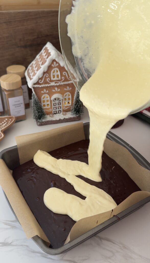 Pouring cheesecake layer over brownie batter (image 2/3)